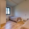 Due letti singoli con copriletti beige, pavimento in legno e una finestra con cornice verde.