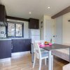 Cucina moderna con mobili scuri, tavolo apparecchiato e divano beige vicino a una finestra.