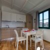 Cucina moderna con tavolo bianco e sedie di legno, pavimento in legno e ampia finestra.