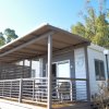 Una casa mobile con ampio portico e sedie, circondata da alberi.