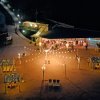 Veduta notturna di una spiaggia illuminata con tavoli coperti e sentiero.