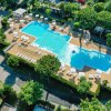 Grande piscina rettangolare circondata da verde e ombrelloni.