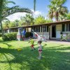 Bambini giocano a calcio nel prato di fronte a bungalow.