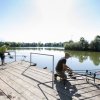 Due persone pescano su una piattaforma vicino a un lago.