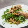 Scampi su rucola e patate conditi con olio.