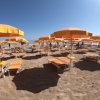 Spiaggia con lettini e ombrelloni arancioni.