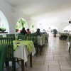 Una sala interna con tavoli coperti da tovaglie verde chiaro e sedie verdi, alcune persone sedute.