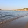 Una spiaggia con onde leggere che lambiscono la riva, vista di una costa lontana.