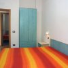 Camera con letto matrimoniale, coperta arancione, armadio azzurro e porta aperta.