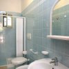Bagno con lavabo, specchio, WC e doccia, piastrelle azzurre.