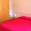 Camera da letto con copriletto rosso, armadio in legno e lampada su un comodino.