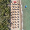 Spiaggia con ombrelloni di paglia visti dall'alto.