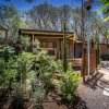 Un bungalow in stile rustico circondato da vegetazione lussureggiante e alberi.