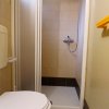 Bagno con doccia, WC e piastrelle chiare; la porta della doccia è scorrevole.