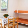 Interno con tavolo apparecchiato e letti a castello con coperte arancioni.