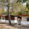 Bungalow tra gli alberi con pareti bianche e tetto marrone.