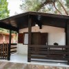 Bungalow in legno con veranda, circondato da alberi.