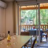 Interno con tavolo, due bicchieri e una bottiglia di vino, vista su terrazza e vegetazione.