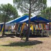 Area picnic sotto un tendone blu e giallo, circondata da tende.