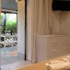 Angolo di una stanza con cassettiera bianca, TV e vista su veranda con tavolo e sedie.