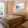 Camera da letto con letto matrimoniale, lenzuola beige, quadro marino e tavolo esterno.