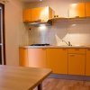 Cucina con mobili arancioni, piano di lavoro e finestra aperta su giardino.