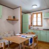 Cucina compatta con mobili verde chiaro, tavolo con due sedie e divanetto fiorito.