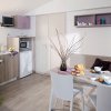 Cucina moderna con tavolo da pranzo, decorazioni semplici e cesto di frutta.