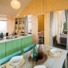 Cucina con dettagli in legno e verde, tavola apparecchiata e accesso a camera da letto.