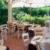 Terrazza di un ristorante con tavoli apparecchiati, circondata dal verde.