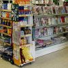 Interno di un negozio con scaffali di riviste, snack e cartoline.