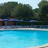 Piscina tranquilla all'aperto con lettini e ombrelloni blu.
