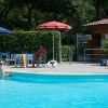 Una piscina circondata da lettini e ombrelloni, con alcune persone a bordo vasca.