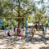 Bambini che giocano su altalene in un parco giochi immerso nella natura.