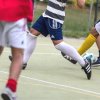 Persone che giocano a calcio su un campo all'aperto, concentrandosi sulle gambe e il pallone.