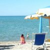 Spiaggia con ombrelloni colorati, sedie a sdraio e persone che si rilassano vicino al mare.
