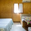 Stanza con pareti in legno, letto matrimoniale, tavolo con tovaglia colorata e aria condizionata.