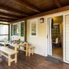Una veranda in legno con tavolo e panche. Porta aperta che conduce all'interno della casa mobile.