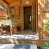 Veranda in legno con tavolo e panca, porta d'ingresso aperta.