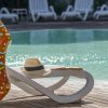 Ciambella gonfiabile e cappello su sedia a sdraio vicino a piscina.