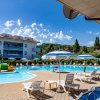 Una piscina con lettini e ombrelloni sotto un cielo blu, edificio sullo sfondo.