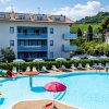 Una piscina con scivoli colorati, sedie a sdraio e un edificio residenziale sullo sfondo.