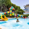 Una piscina con scivoli d'acqua colorati e un bambino che gioca nell'acqua.