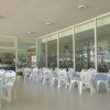 Esterno di un bar con tavoli e sedie bianche di plastica disposti ordinatamente.