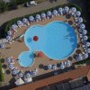 Vista aerea di una piscina con ombrelloni allineati lungo il perimetro.