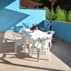 Terrazza con tavolo bianco, sedie e piante in vaso.
