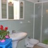Bagno con lavabo, bidet, doccia, specchio, armadietto e pianta fiorita su mobile blu.