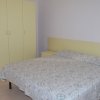 Camera da letto con letto matrimoniale, copriletto decorato, armadio giallo chiaro e comodini.