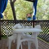 Tavolo bianco con sedie in plastica su una veranda con vista su un giardino alberato.
