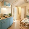 Cucina moderna con mobili blu, tavolo apparecchiato e divanetto verde.